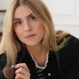 Kasia Tusk, z blond włosami i w jeansach, trzyma pędzel do makijażu. Wiele osób zastanawia się, ile lat ma Kasia Tusk.