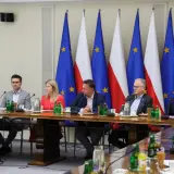 Ludzie przy stole, flagi Polski i UE w tle. Czy to spotkanie, na którym rzecznicy PiS unikają odpowiedzi na pytania o relacje z Suwerenną Polską?