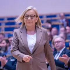 Kobieta w garniturze, minister klimatu, idzie przez salę pełną ludzi. Konfederacja ujawnia prawdziwe powody dla których złożyła wniosek o odwołanie ministry klimatu.