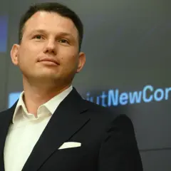 Kto finansuje luksusowe spotkania wyborcze Mentzena w największych miastach Polski? Mężczyzna w garniturze na tle ekranu z napisem "NewConnect".