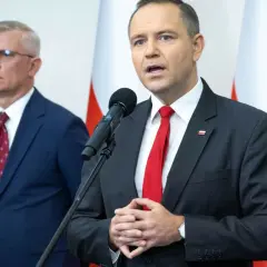 Mężczyzna w garniturze mówi do mikrofonu, obok stoi drugi mężczyzna. Dyskutują, dlaczego prezydent chce zwiększenia budżetu na Biuro Bezpieczeństwa Narodowego o 15 procent.