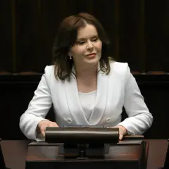Anna Krupka w białej marynarce przy mównicy. Czy wiceprezes PiS nie dostaje pieniędzy za funkcję?