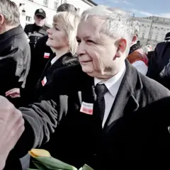 Jarosław Kaczyński ściska dłoń, w tle ludzie i czerwone balony.