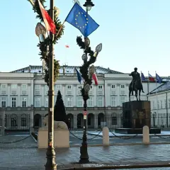 Pałac Prezydencki w Warszawie z pomnikiem konnym i flagami.