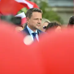 Kto stoi za nowym wizerunkiem kandydata KO na prezydenta i ile to kosztowało? Mężczyzna w garniturze na tle flag.