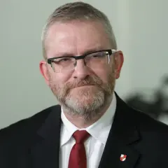 Grzegorz Braun w garniturze i krawacie, z okularami i brodą. Czy zostanie wykluczony z klubu za kontrowersyjne wypowiedzi o Izraelu?