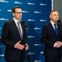 Mateusz Morawiecki i Andrzej Duda stoją przy mikrofonach. Andrzej Duda wzrostem przewyższa premiera.