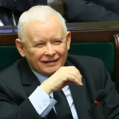 Jarosław Kaczyński w garniturze, siedzi w fotelu, uśmiecha się.
