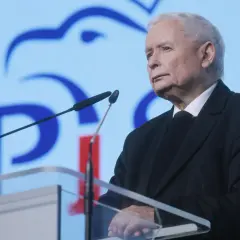 Jarosław Kaczyński przemawia na tle niebieskiego ekranu z logo PiS.