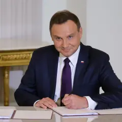 Prezydent Duda w garniturze podpisuje dokument. Ile lat ma Duda? To pytanie, na które odpowiedź znajdziemy w jego biografii.