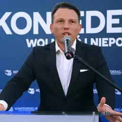 Mężczyzna w garniturze przemawia do mikrofonu na tle baneru Konfederacji. Dyskutuje, dlaczego KO chce odebrać dotacje partii opozycyjnej poprzez nowelizację kodeksu wyborczego.