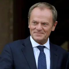 Donald Tusk w garniturze i krawacie, uśmiecha się.