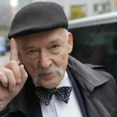 Janusz Korwin-Mikke w czapce i muszce, unoszący palec, budzi spekulacje fanów Konfederacji o jego powrocie.