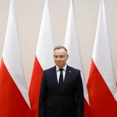 Prezydent Duda stoi przed polskimi flagami. Zastanawiamy się, dlaczego prezydent nie podpisał ustawy o mowie nienawiści przed marcem 2026.