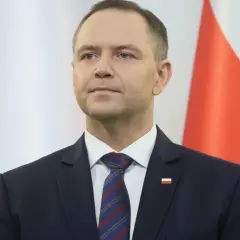 Mężczyzna w garniturze przed polską flagą. Czy to symbol ukrytych kosztów utrzymania Kancelarii Prezydenta RP w ostatnim roku kadencji?