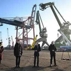 Ludzie stojący przed dźwigami portowymi w Gdańsku.