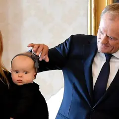 Kasia Tusk z dziećmi, Donald Tusk delikatnie dotyka główki niemowlaka.