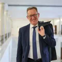 Uśmiechnięty mężczyzna w garniturze, który może być powiązany z pytaniem, dlaczego Robert Telus i Rafał Romanowski zostali zawieszeni w prawach członka.