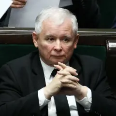 Jarosław Kaczyński w garniturze z splecionymi dłońmi, siedzi w ławach sejmowych.