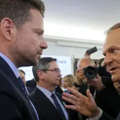 Czy Donald Tusk rzeczywiście obawia się ambicji prezydenckich Rafała Trzaskowskiego? Politycy rozmawiają w tłumie, w tle dziennikarze z aparatami.