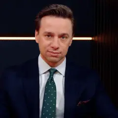 Krzysztof Bosak w garniturze, z zielonym krawatem w kropki. Mówi o tym, dlaczego uważa, że polska polityka zagraniczna nie jest asertywna.