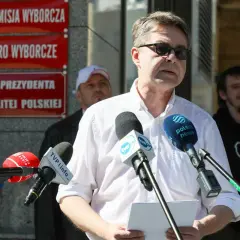 Mężczyzna przemawia do mediów przed budynkiem z napisem "Kancelaria Prezydenta RP". Dyskutuje się, dlaczego Pałac Prezydencki został wyłączony z części audytów dotyczących lotów państwowych.