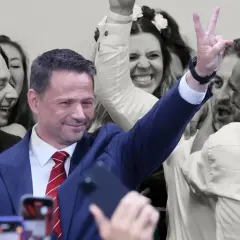 Karol Nawrocki z uśmiechem i gestem zwycięstwa, otoczony entuzjastycznym tłumem. To obraz, który może sugerować, dlaczego Karol Nawrocki wygrywa w najnowszych sondażach prezydenckich z marca 2026.