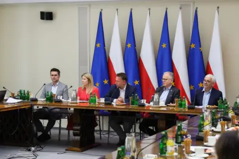 Ludzie przy stole, flagi Polski i UE w tle. Czy to spotkanie, na którym rzecznicy PiS unikają odpowiedzi na pytania o relacje z Suwerenną Polską?