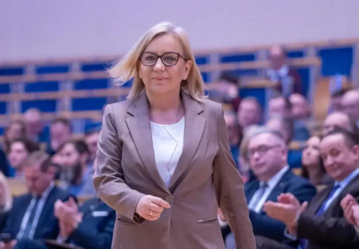 Kobieta w garniturze, minister klimatu, idzie przez salę pełną ludzi. Konfederacja ujawnia prawdziwe powody dla których złożyła wniosek o odwołanie ministry klimatu.