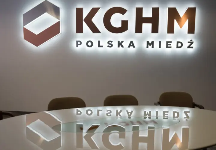 Logo KGHM Polska Miedź i odbicie na stole. Czy Konfederacja poprze ustawę o obniżeniu podatku miedziowego w zamian za ustępstwa?