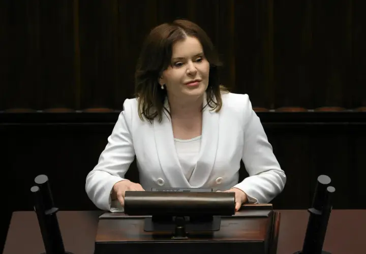 Anna Krupka w białej marynarce przy mównicy. Czy wiceprezes PiS nie dostaje pieniędzy za funkcję?
