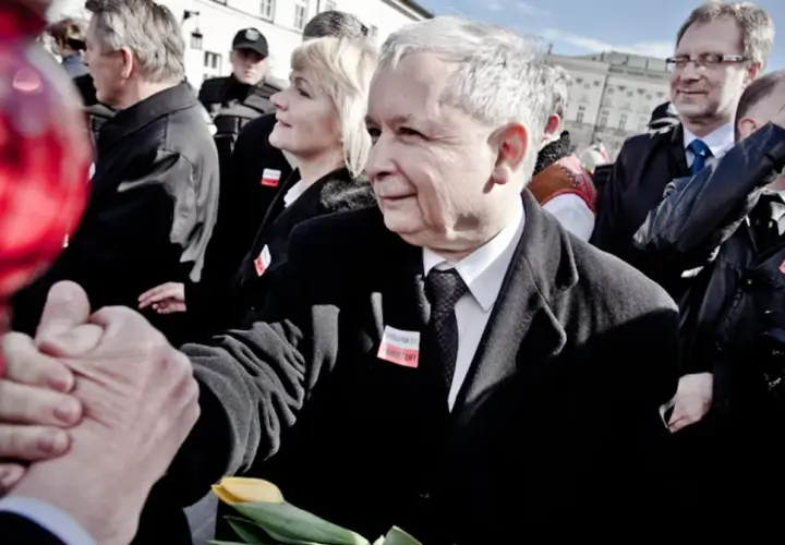 Jarosław Kaczyński ściska dłoń, w tle ludzie i czerwone balony.