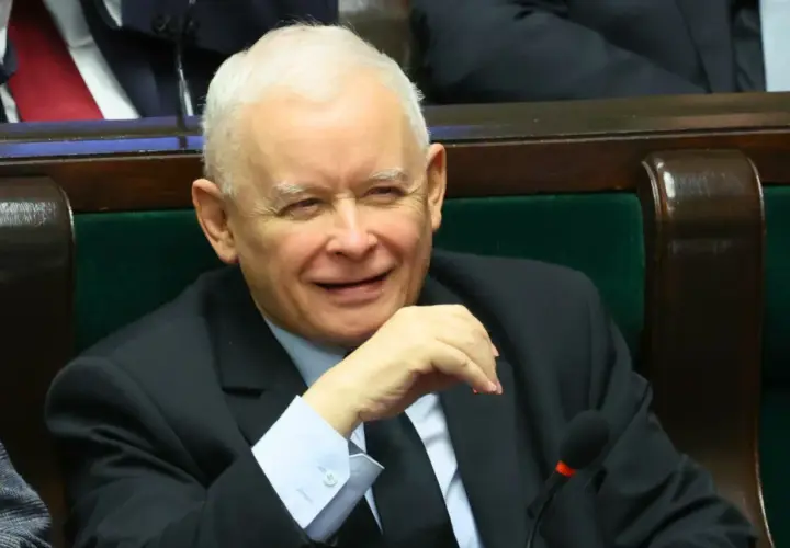 Jarosław Kaczyński w garniturze, siedzi w fotelu, uśmiecha się.