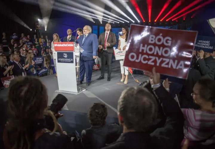 Kto z polityków Konfederacji stoi za nowym projektem ustawy o dobrowolnym ZUS? Na scenie przemawia Krzysztof Bosak, a obok niego stoją inni politycy partii.