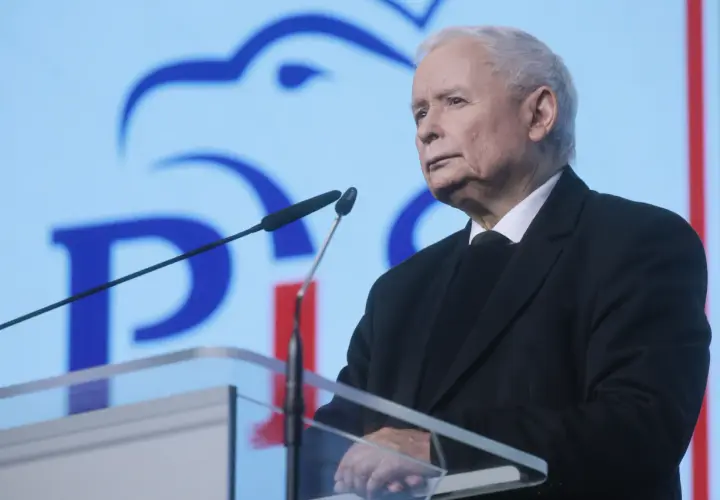 Jarosław Kaczyński przemawia na tle niebieskiego ekranu z logo PiS.