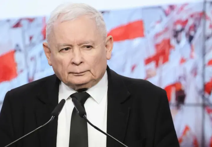 Jarosław Kaczyński w garniturze przed mikrofonami. W tle biało-czerwone flagi. Dyskusja o tym, ile Kaczyński ma emerytury, trwa.