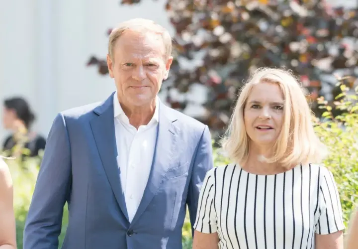 Donald Tusk z żoną, Małgorzatą. Stoją obok siebie, uśmiechają się do obiektywu.