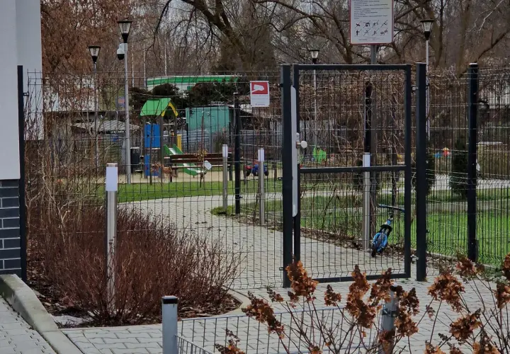 Prawda o ustawie która ma zakazać grodzenia osiedli w dużych miastach: ogrodzony plac zabaw z bramą i tablicą informacyjną.