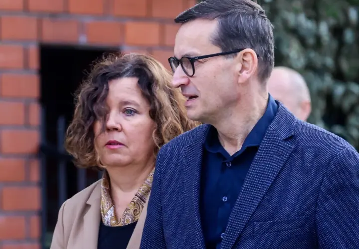 Iwona i Mateusz Morawieccy w zbliżeniu, na tle ceglanego muru.