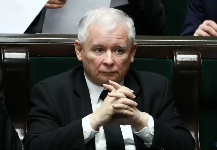 Jarosław Kaczyński w garniturze z splecionymi dłońmi, siedzi w ławach sejmowych.