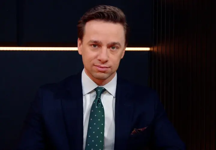Krzysztof Bosak w garniturze, z zielonym krawatem w kropki. Mówi o tym, dlaczego uważa, że polska polityka zagraniczna nie jest asertywna.