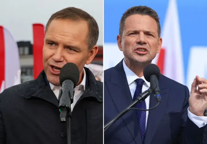 Dwaj mężczyźni w garniturach przemawiający do mikrofonów na tle flag.