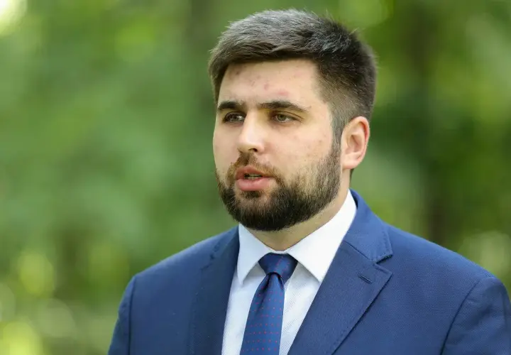 Młody mężczyzna w garniturze, Jakubas Banaszek, budzi zaskoczenie działaczy swoją kandydaturą na premiera.