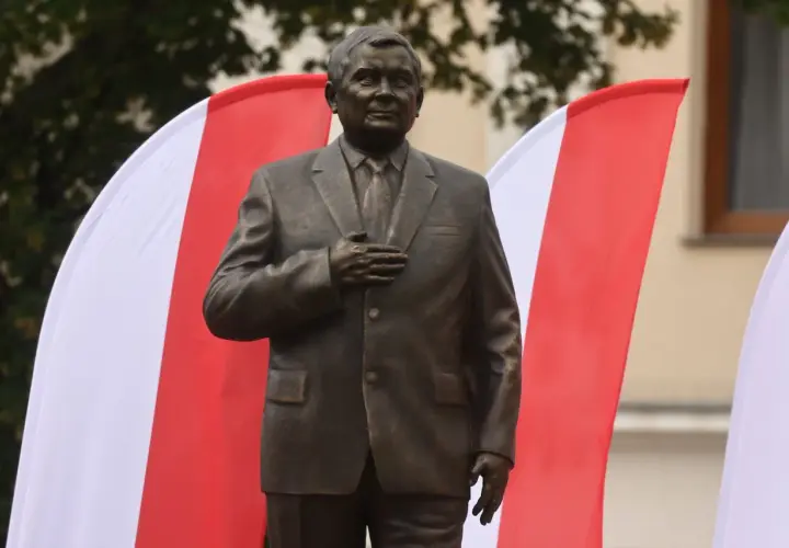 Pomnik Lecha Kaczyńskiego, jednego z wielu w Polsce, stoi na tle biało-czerwonych flag.