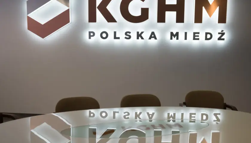 Logo KGHM Polska Miedź i odbicie na stole. Czy Konfederacja poprze ustawę o obniżeniu podatku miedziowego w zamian za ustępstwa?