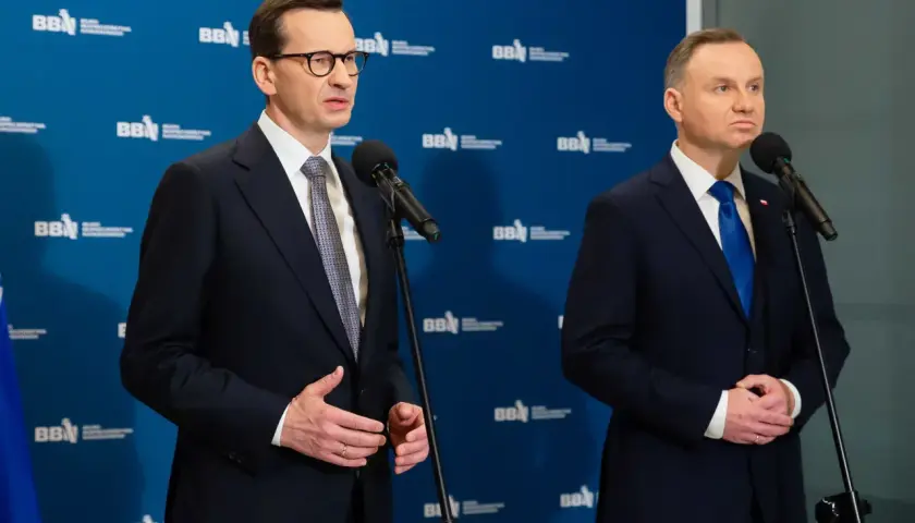 Mateusz Morawiecki i Andrzej Duda stoją przy mikrofonach. Andrzej Duda wzrostem przewyższa premiera.