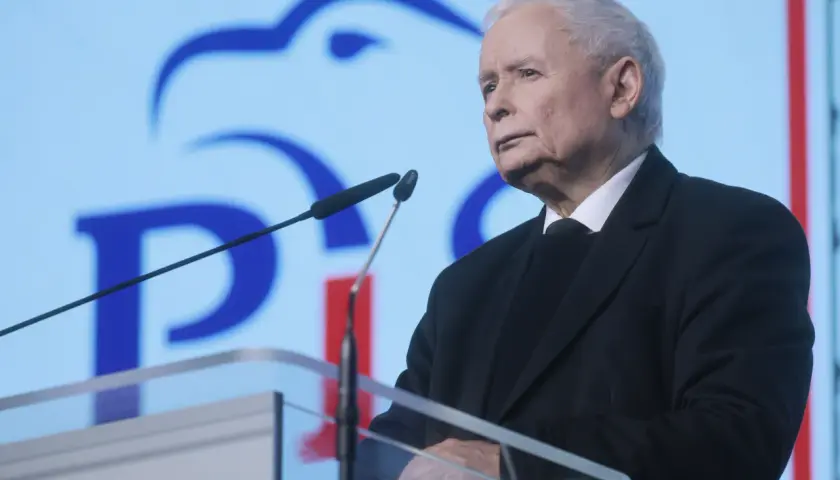 Jarosław Kaczyński przemawia na tle niebieskiego ekranu z logo PiS.