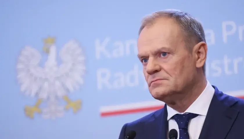 Donald Tusk w garniturze, za nim godło Polski. Czy prezydent ma prawo ogłosić referendum w sprawie CPK bez zgody sejmu?