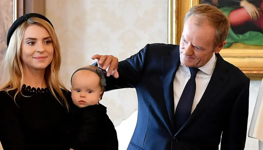 Kasia Tusk z dziećmi, Donald Tusk delikatnie dotyka główki niemowlaka.