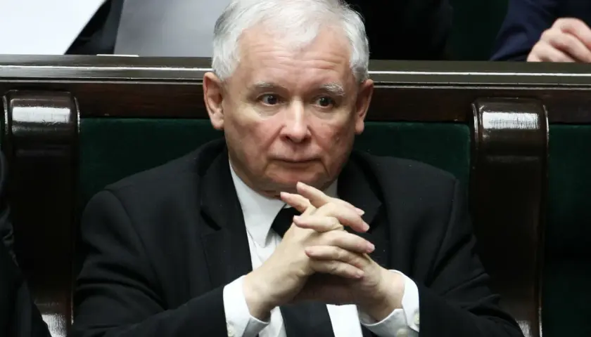 Jarosław Kaczyński w garniturze z splecionymi dłońmi, siedzi w ławach sejmowych.